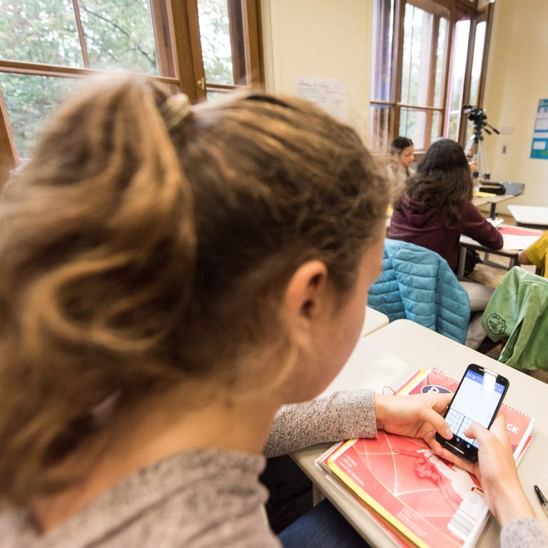 Schülerin mit dem Smartphone im Schulunterricht. (Foto: dpa Bildfunk, Picture Alliance)