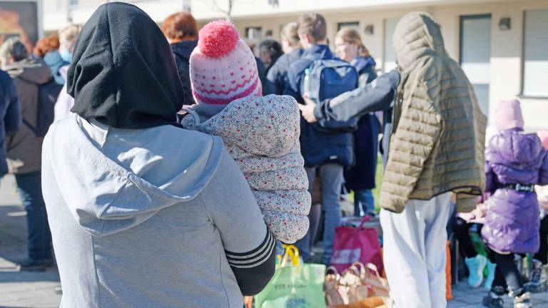 Flüchtlinge aus der Ukraine stehen mit ihrem Gepäck vor einer Asylunterkunft an