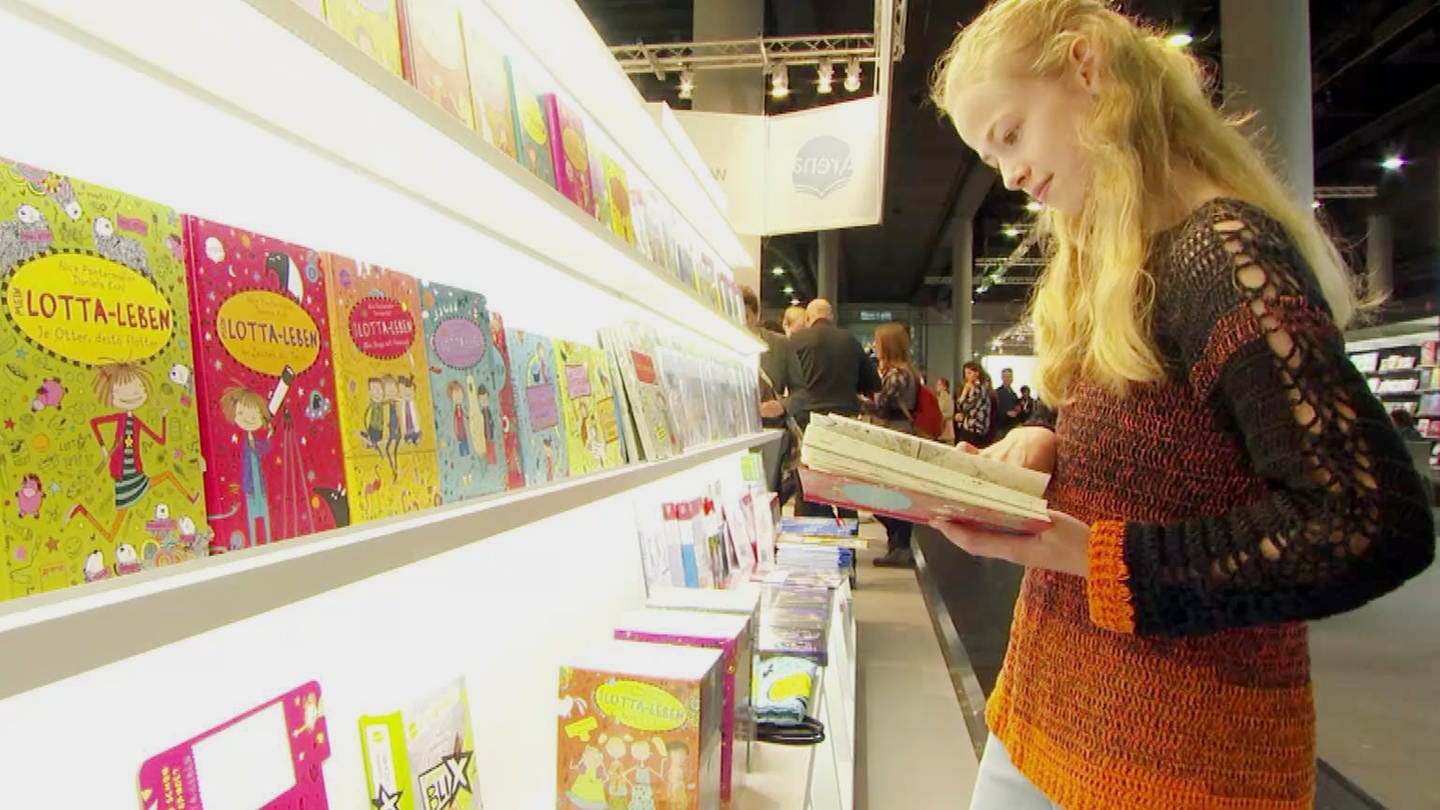 eine junge Lesebegeisterte stöbert in einem Buch (Foto: SWR)