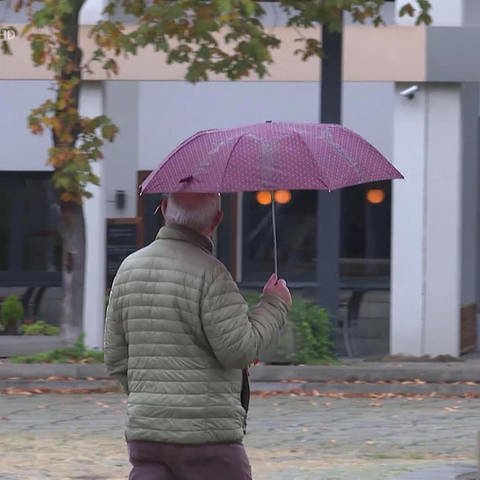 Mann mit Regenschirm unterwegs in Ludwigshafen