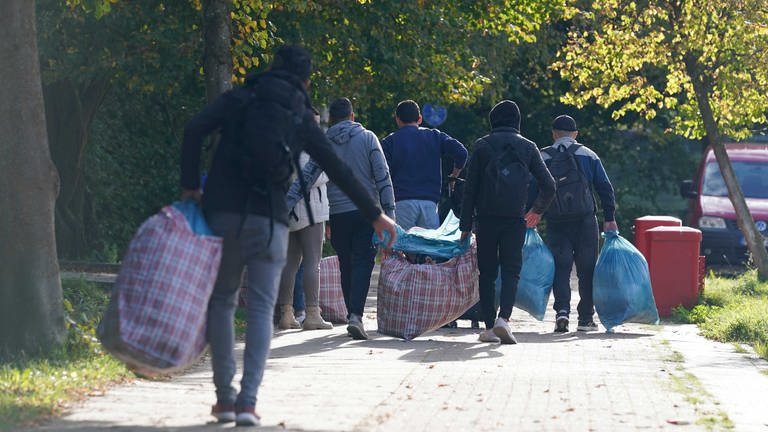 Flüchtlinge aus Syrien gehen mit ihrem Gepäck zu einer Erstaufnahmeeinrichtung.