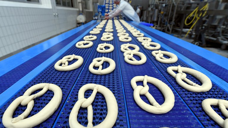 Geformter Brezelteig läuft über eine Produktionslinie im Werk der Großbäckerei Ditsch.