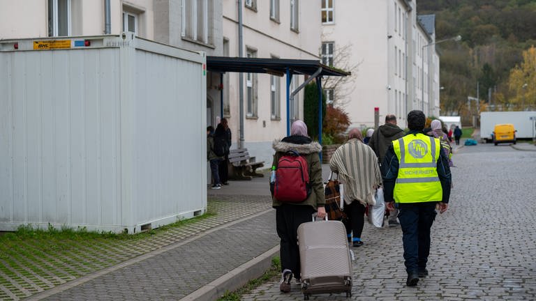 Neuangekomme Flüchtlinge gehen mit ihren Koffern in eines der Wohnhäuser der Aufnahmeeinrichtung für Asylbegehrende (AfA) in Trier. (Foto: dpa Bildfunk, Picture Alliance)
