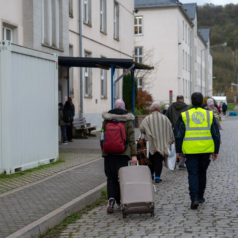 Neuangekomme Flüchtlinge gehen mit ihren Koffern in eines der Wohnhäuser der Aufnahmeeinrichtung für Asylbegehrende (AfA) in Trier.
