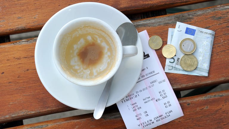Münzen, ein Geldschein und eine Rechnung liegen neben einer leeren Kaffeetasse auf einem Tisch in einem Restaurant. (Foto: dpa Bildfunk, Tobias Hase)