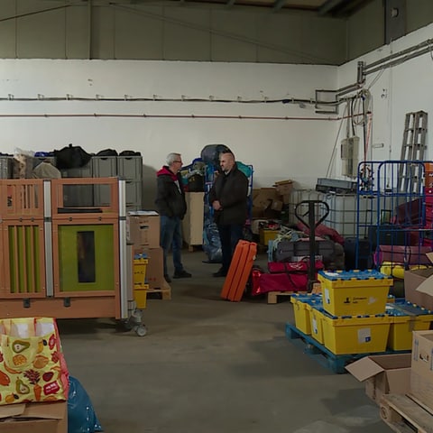 Zwei Männer stehen in Lagerhalle mit Hilfstgütern