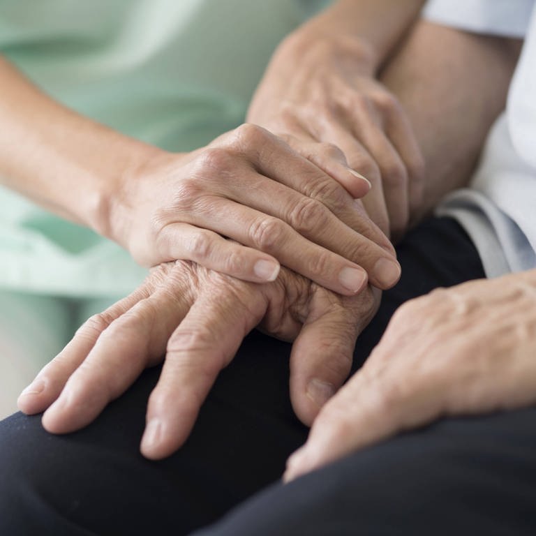 Ältere Hand wird von zwei jüngeren Händen einfühlsam gehalten (Foto: IMAGO, Science Photo Library)