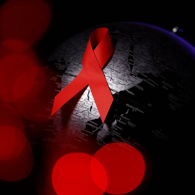 Es ist das für AIDS bekannte Symbol der roten Schleife zu sehen, auf einem schwarzen Hintergrund. (Foto: IMAGO, Panama Pictures)