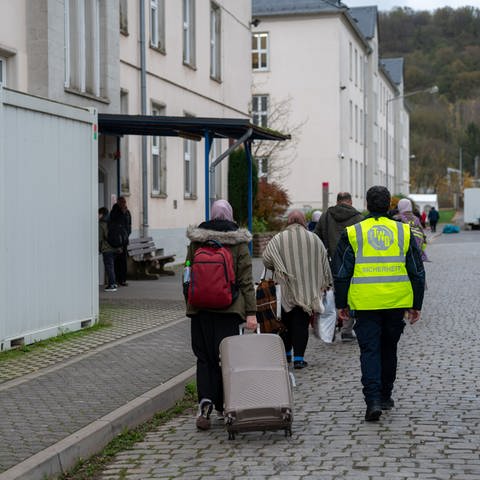 Neuangekomme Flüchtlinge gehen mit ihren Koffern in eines der Wohnhäuser der Aufnahmeeinrichtung für Asylbegehrende (AfA) in Trier. (Foto: dpa Bildfunk, Picture Alliance)