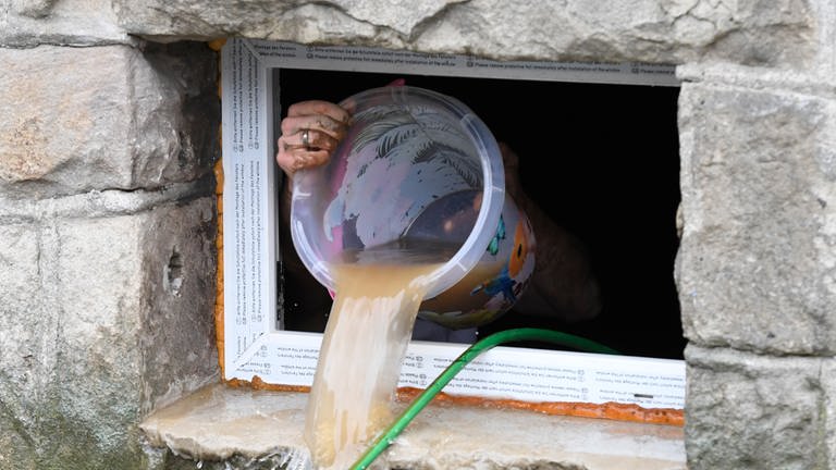 Ein Frau schöpft mit einem Einmer Wasser aus einem überfluteten Keller.  (Foto: dpa Bildfunk, Picture Alliance)