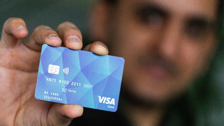 Ein Geflüchteter hält eine Debitcard in der Hand, die der Ortenaukreis als Bezahlkarte für Geflüchtete ausgibt.