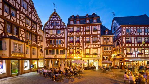 Giebelfachwerkhäuser am belebten mittelalterlichen Marktplatz am Abend, Bernkastel-Kues.