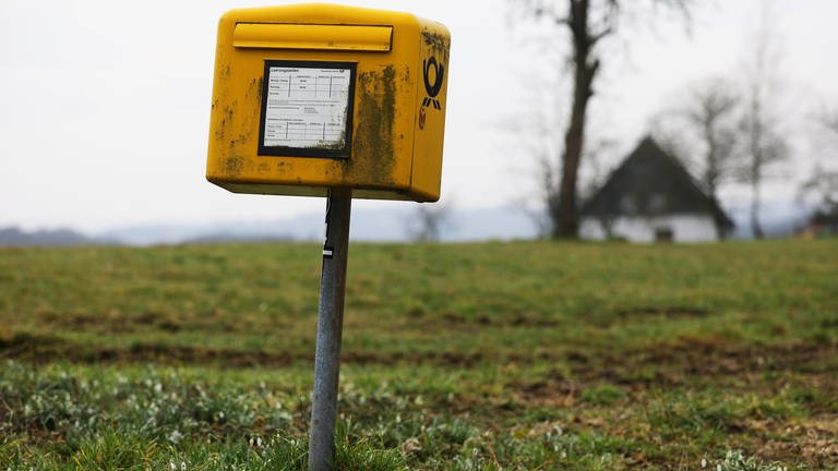 Ein verdreckter Briefkasten auf einer Wiese. (Foto: dpa Bildfunk, Picture Alliance)