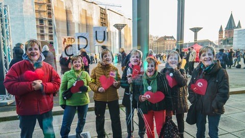 Demonstranten mit Merkel-Masken bei CDU-Veranstaltung in Mainz (Foto: SWR)