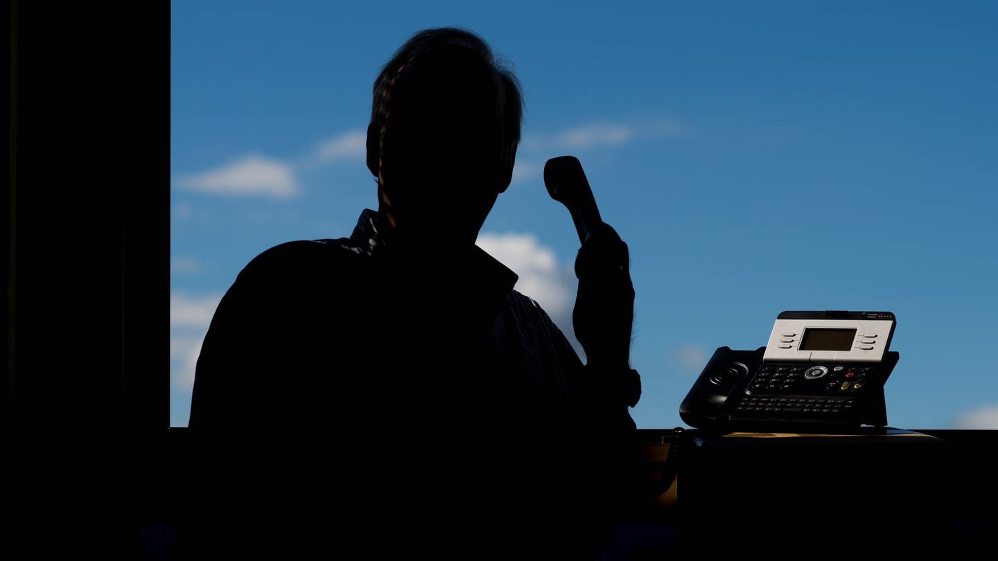 Ein Mann im Schatten mit einem Telefon (Foto: dpa Bildfunk, Picture Alliance)