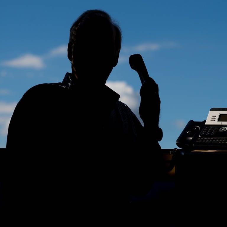 Ein Mann im Schatten mit einem Telefon 