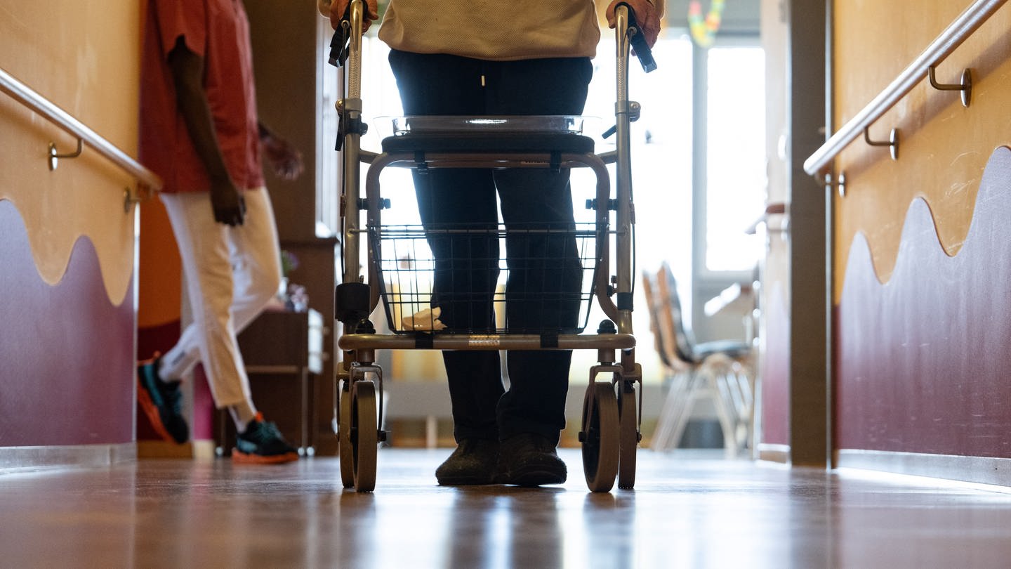 Ein Bewohner eines Pflegeheims geht mit einem Rollator einen Gang entlang. (Foto: picture-alliance / Reportdienste, picture alliance/dpa | Marijan Murat)
