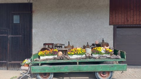 Ein Wagen voller Blumen im Schwarzwald vor einer Scheune.