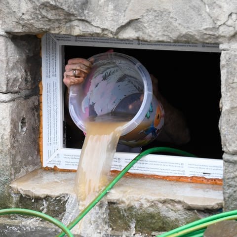 Ein Anwohner beseitigt seine Schäden im Keller, in dem er kurzerhand das Wasser mit einem Eimer aus dem Keller befördert, die das Hochwasser mit sich gebracht hat. 