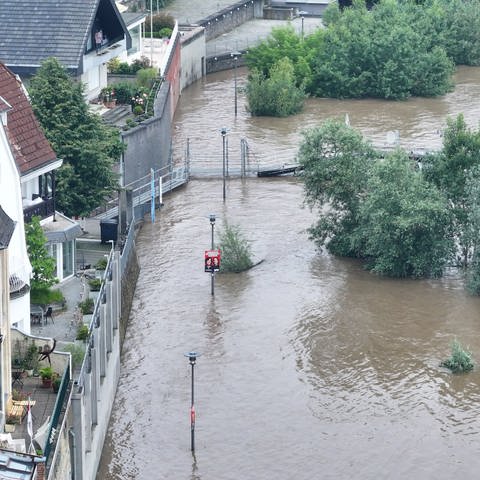 Das Wasser des Rheins steht hoch und nahe an Häusern, die durch Spundwände und Mauern gesichert sind.