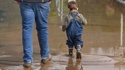 Ein Kind stapft durch das Wasser am Moselufer in Koblenz Güls. Die Schifffahrt an Saar und Mosel ist für Personenschifffahrt eingestellt. Ausflugstouren für Familien können seit Freitag wegen des Unwetters und der stark gestiegenen Pegelstände nicht stattfinden.