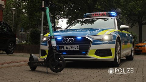 Ein E-Scooter steht vor einem Polizeiauto. (Foto: Polizeipräsidium Westpfalz)