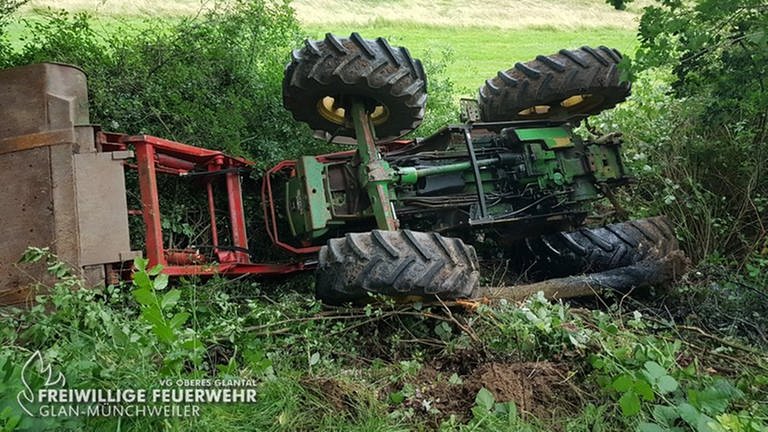 Ein Traktor liegt auf dem Kopf am Fuß einer Böschung (Foto: Freiwillige Feuerwehr Glan-Münchweiler)