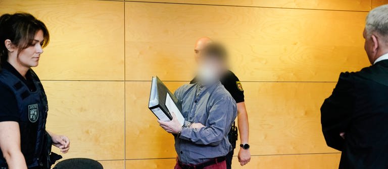 Der 39-jährige Hauptangeklagte im Fall der getöteten Polizisten im Kreis Kusel kommt mit Handschellen in den Verhandlungssaal des Landgerichts Kaiserslautern. (Foto: dpa Bildfunk, picture alliance/dpa/dpa-Pool | Uwe Anspach)