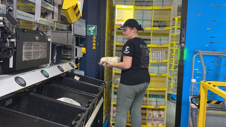 Amazon-Mitarbeiterin Sabrina Jancys gefällt die Arbeit im Logistikzentrum. Hier ist sie gerade beim "Picken". Sie sammelt also die Bestellungen der Kunden ein und schickt sie mit einer Kiste über ein Laufbahn zu den Kollegen. Dort werden die Artikel eingepackt. (Foto: SWR)
