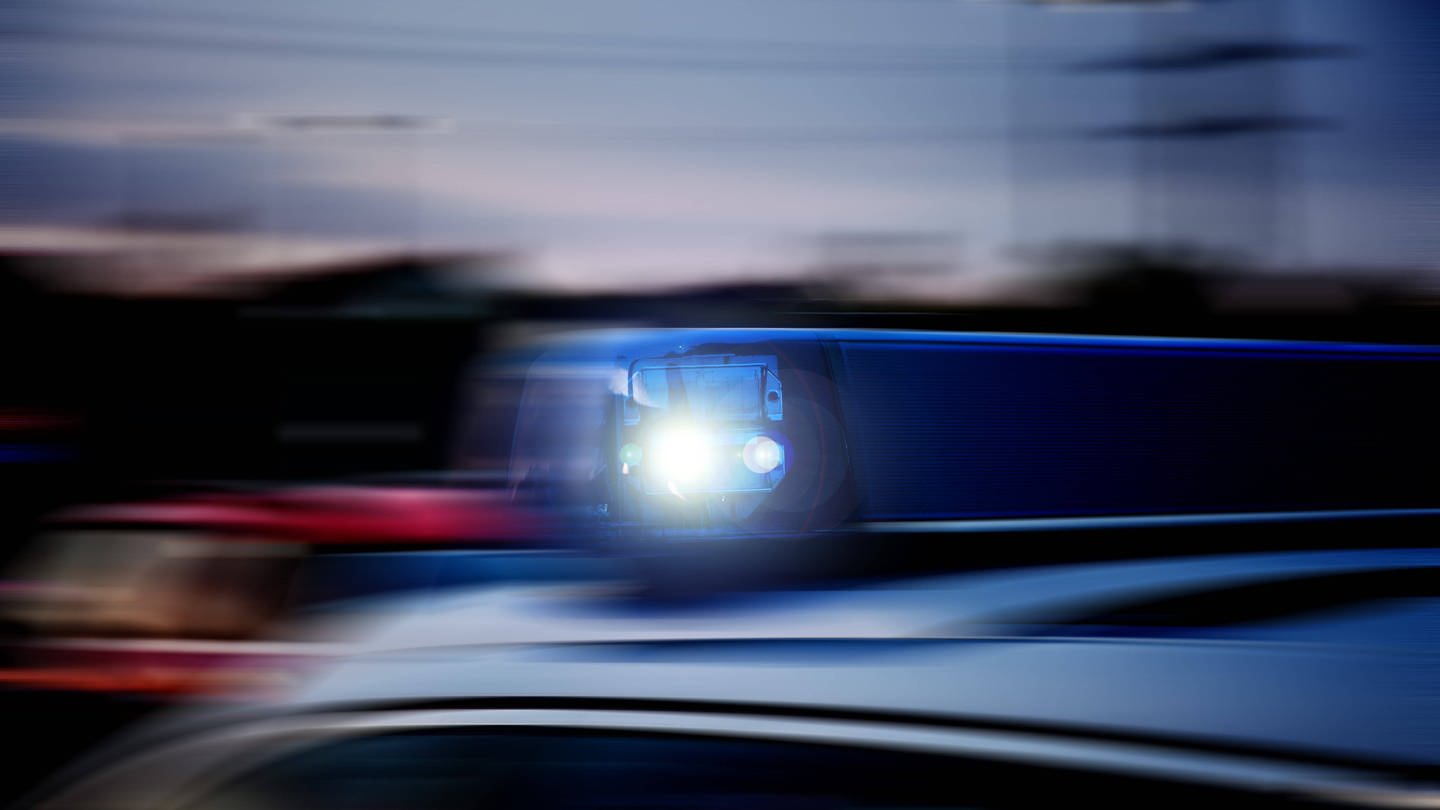 Verwackeltes Blaulicht auf einem schnellfahrenden Polizeifahrzeug im Einsatz. (Foto: IMAGO, Fotostand)
