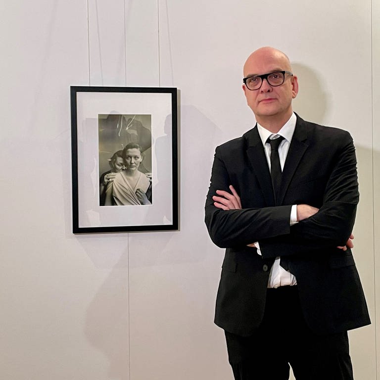 Der Fotomedia-Künstler Boris Eldagsen neben seinem Bild "Electrician", das mit Hilfe Künstlicher Intelligenz (KI) generiert wurde. (Foto: SWR)