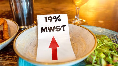 Mehrwertsteuererhöhung in der Gastronomie: 19 Prozent Mehrwersteuer Text auf einer Serviette in einem Teller. (Foto: IMAGO, Mehrwertsteuer)