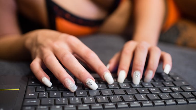 Eine Frau mit lackierten Nägeln tippt auf einem Computer.  (Foto: dpa Bildfunk, picture alliance / dpa | Matthias Balk)