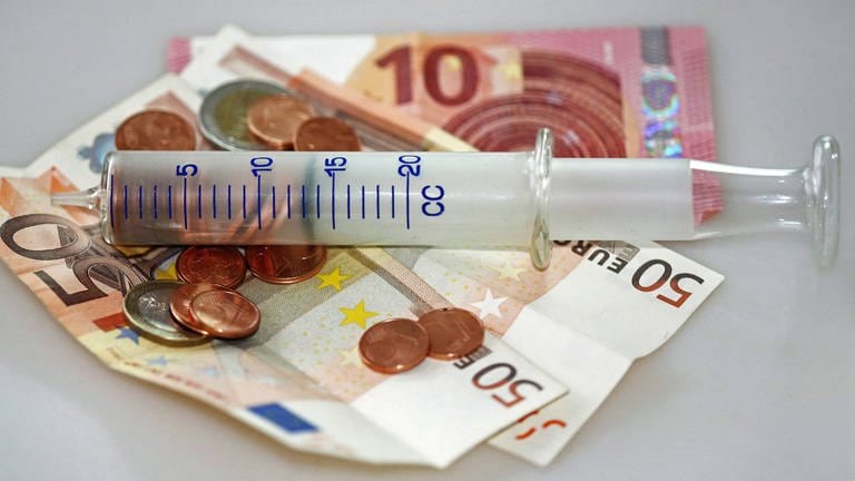 Westpfalz-Klinikum bekommt Millionen von Kommunen - eine Spritze liegt auf einem Bündel Geldscheinen (Foto: IMAGO, IMAGO / Gerhard Leber)