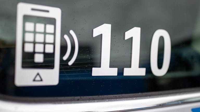 Der Nummer des Polizeinotrufs 110 steht auf der Scheibe eines Polizeifahrzeugs.  (Foto: dpa Bildfunk, picture alliance/dpa | Daniel Karmann)