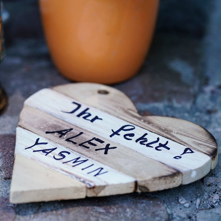 Auf einem Holzbrett in Herzform ist an einer Landstraße zwischen Kusel und Ulmet an einer Gedenkstätte für zwei getötete Polizisten die Aufschrift „Ihr fehlt! Alex Yasmin“ aufgebracht. (Foto: dpa Bildfunk, picture alliance/dpa | Uwe Anspach)
