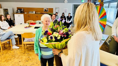 Ein großes Engagement für die Ausbildung im Norden der Pfalz: Martina Leib-Herr, die Direktorin des Evangelischen Diakoniewerks Zoar, bedankt sich bei Gerda Gauer mit einem Strauß Blumen. (Foto: SWR)