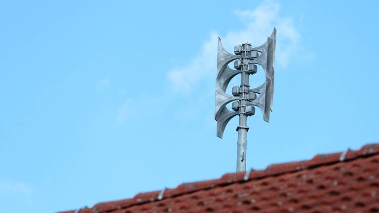 Eine Sirene zur Warnung vor Gefahren ist auf einem Hausdach installiert. (Foto: IMAGO, IMAGO / Jan Huebner)