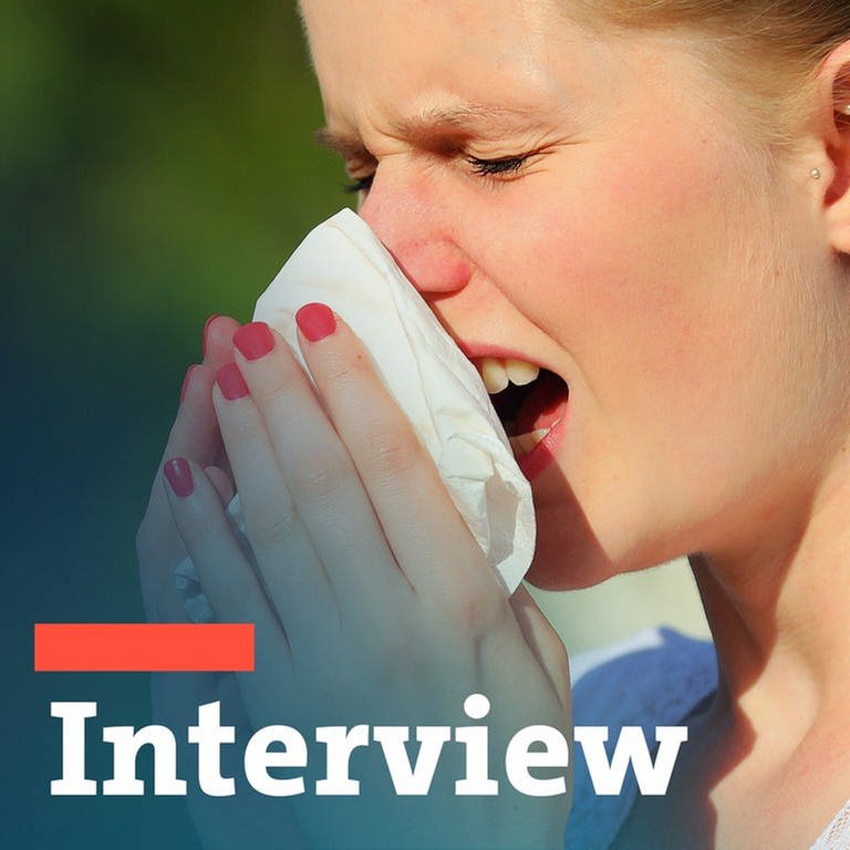 Eine Frau mit Allergie niest in ein Taschentusch - Interview zum Thema Heuschnupfen