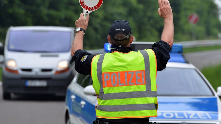Ein Polizist hält ein Auto an: Die Polizei im Westen der Pfalz hat mehr als 500 Autofahrer auf Alkohol und Drogen kontrolliert. Dabei wurden diverse Verstöße festgestellt.