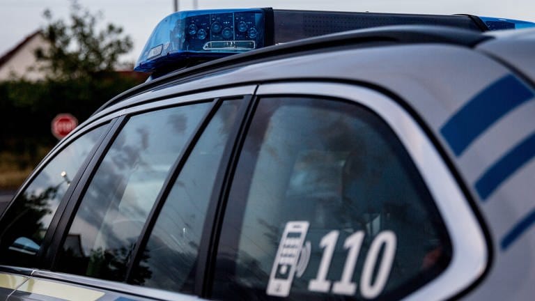 Nachbar in Pirmasens schwer mit Metallstange verletzt - Polizeiauto mit Blaulicht an einer Straße