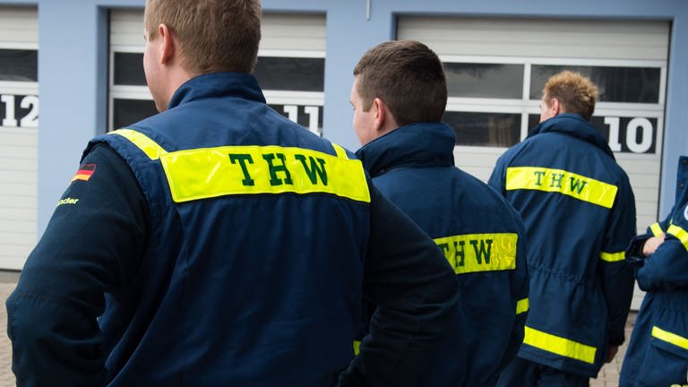 Drei Helfer des THW in Uniform. (Foto: dpa Bildfunk, picture alliance / dpa | Sebastian Kahnert)