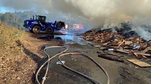 Großbrand von Holz in Weilerbach - Bagger zieht Holz auseinander