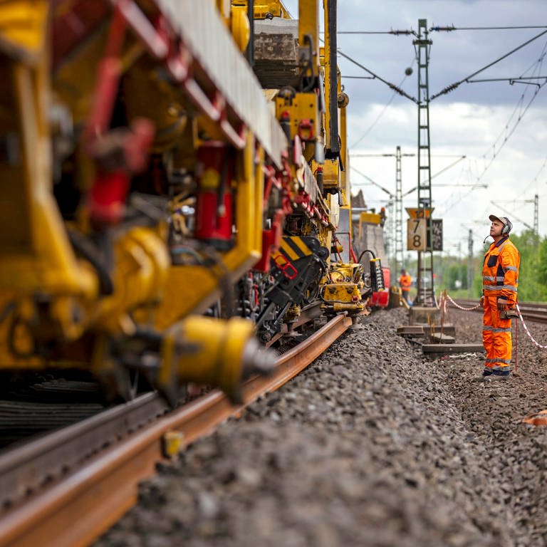 Streit zwischen Zweckverband und Bahn über Bauarbeiten bei Zweibrücken - Baumaschine arbeitet an Gleisen