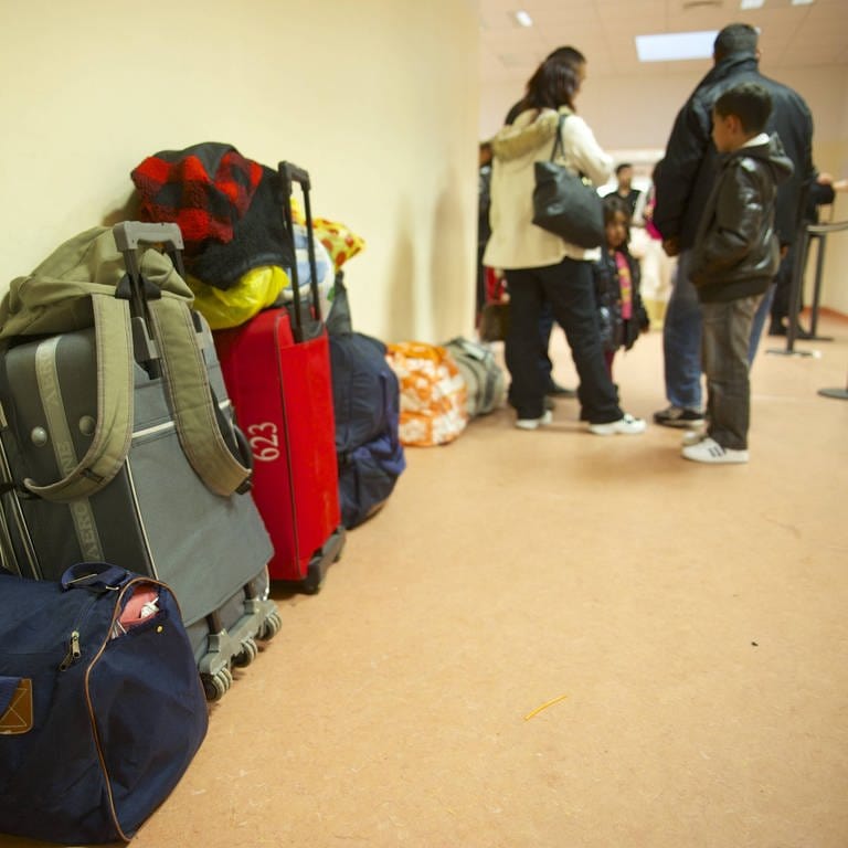 Eine Flüchtlingsfamilie wartet samt Gepäck in einer Aufnahmeeinrichtung. (Foto: IMAGO, IMAGO / Rolf Zöllner)