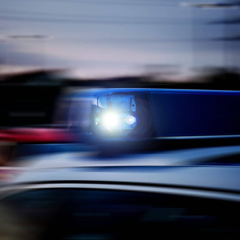 Verwackeltes Blaulicht auf einem schnellfahrenden Polizeifahrzeug im Einsatz.  (Foto: IMAGO, Fotostand)
