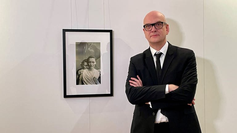 Der Fotomedia-Künstler Boris Eldagsen neben seinem Bild "Electrician", das mit Hilfe Künstlicher Intelligenz (KI) generiert wurde. (Foto: SWR)