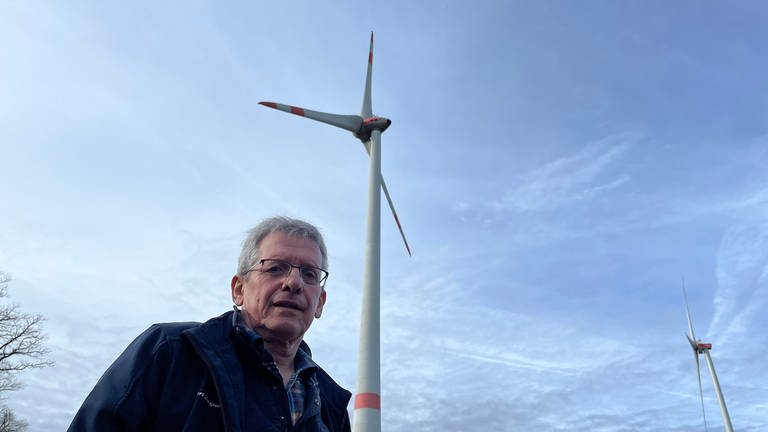 Bürgermeister Albert Ziegler (SPD) steht vor einigen Windrädern seiner Gemeinde Kriegsfeld im Donnersbergkreis. Hier wurden einige der ersten Windräder im Land errichtet.