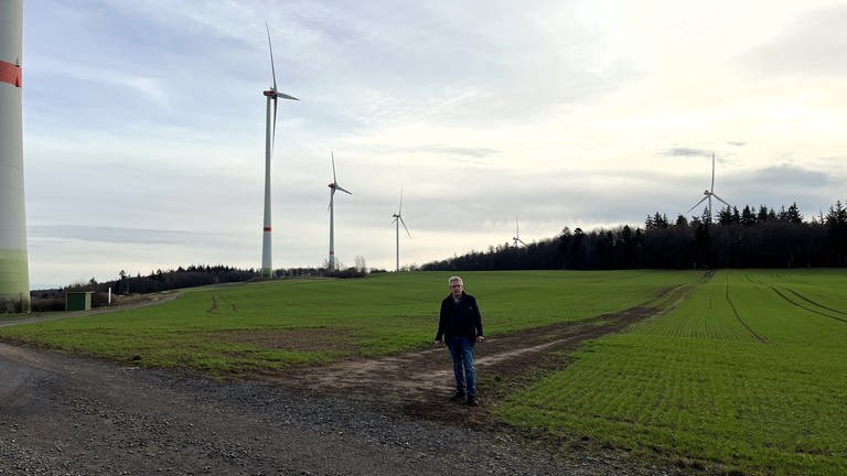 Bürgermeister Albert Ziegler (SPD) steht vor einigen Windrädern seiner Gemeinde Kriegsfeld im Donnersbergkreis. Hier wurden einige der ersten Windräder im Land errichtet. (Foto: SWR)