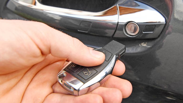 Ein Mann hält den Keyless-Go-Schlüssel eines Autos in der Hand.